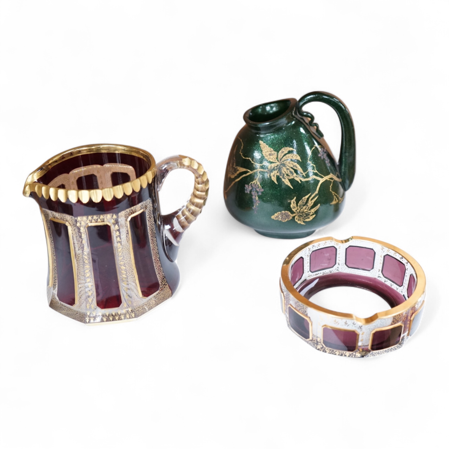 Three pieces of Bohemian and Austrian glassware comprising two jugs and an ashtray, largest 17cm high